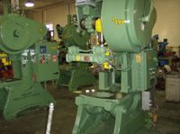 A green machine is sitting in a warehouse next to another machine.