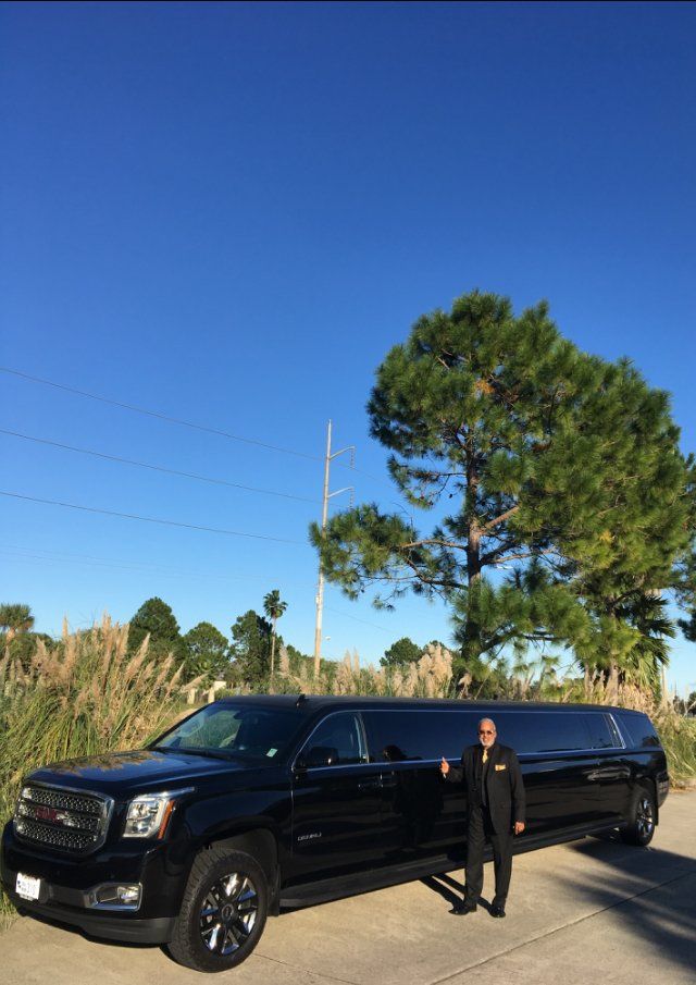 A man is standing in front of a black limousine.