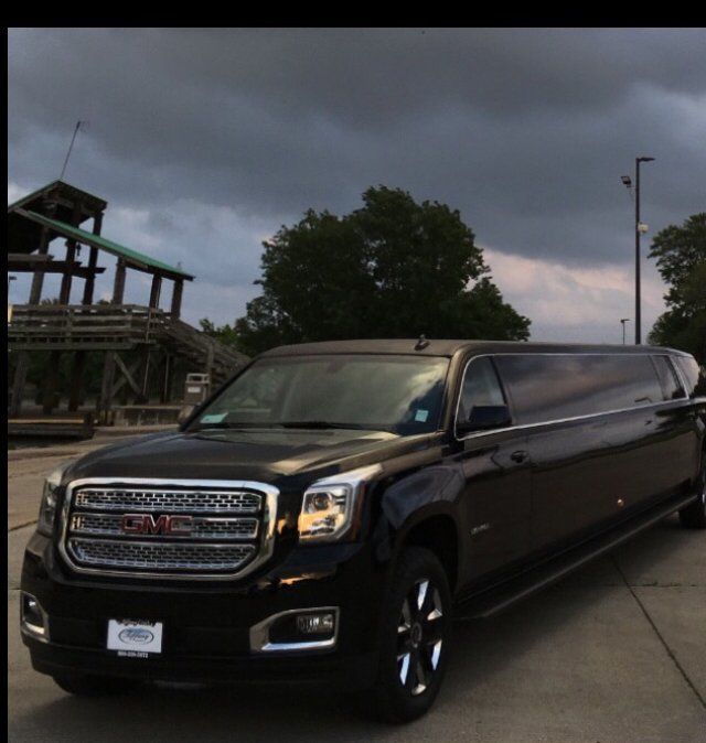 A black gmc limousine is parked in a parking lot