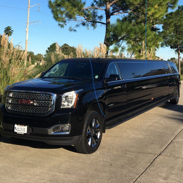 A black gmc limousine is parked on the side of the road