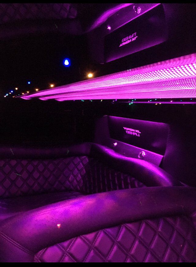 The inside of a limousine with purple lights on the ceiling