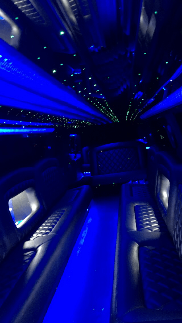 The inside of a limousine with blue lights on the ceiling.