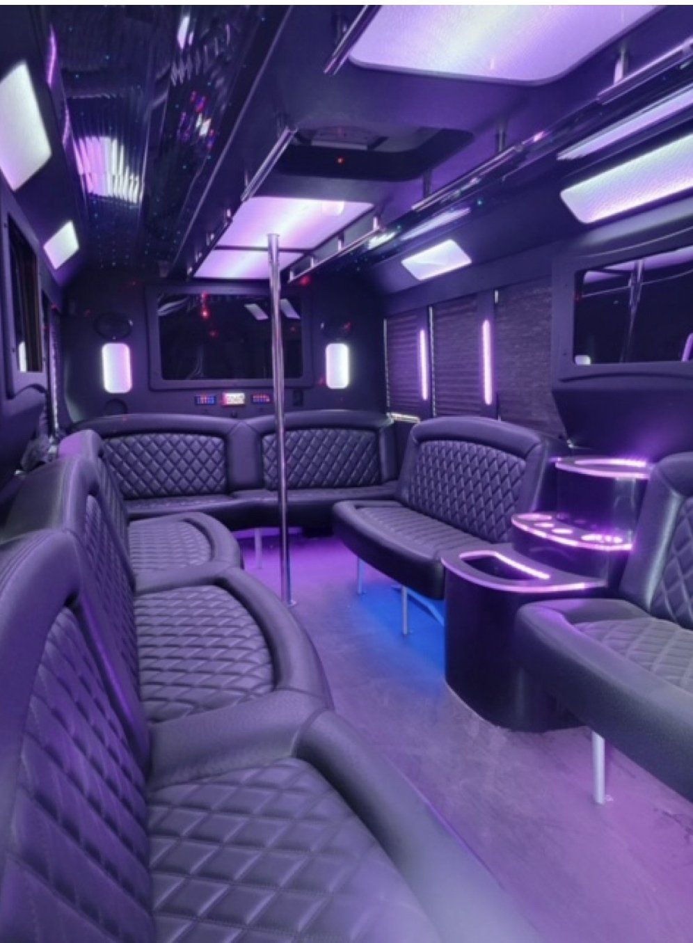 The inside of a party bus with purple seats and tables.
