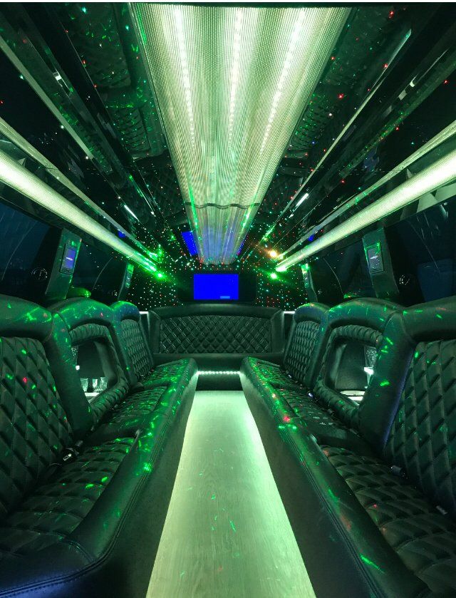The inside of a limousine with green lights on the ceiling.