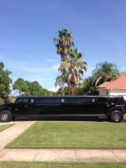 A black limousine is parked in the driveway of a house