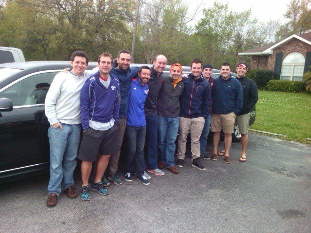 A group of men are posing for a picture in front of a limousine