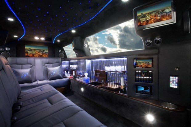 The inside of a limousine with a bar and televisions.