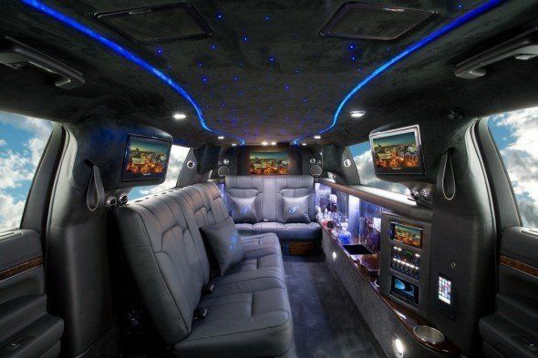 The inside of a limousine with two televisions on the headrests.