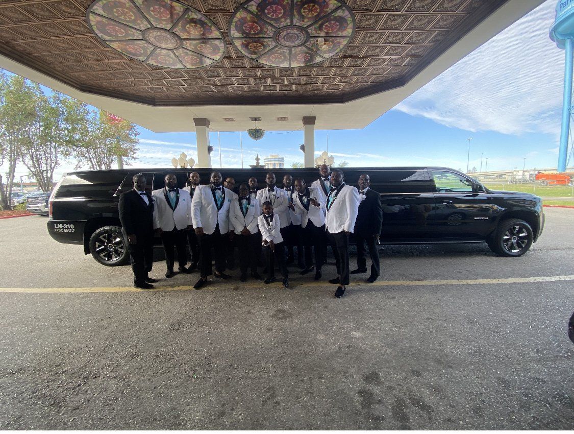 A group of men are standing in front of a limousine.