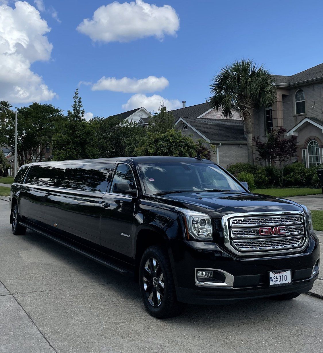 A black gmc yukon limousine is parked on the side of the road