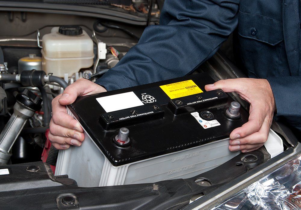 Person Changing The Battery — Hagerstown, MD — Guaranteed Truck & Auto Repair