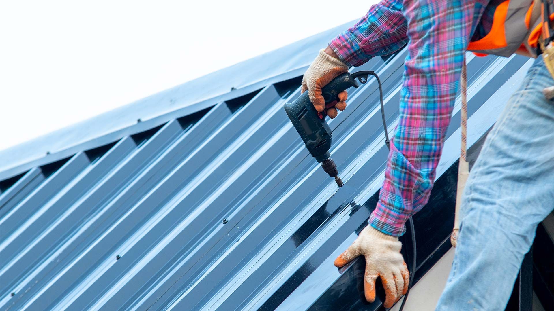 A man is using a drill to install a metal roof.