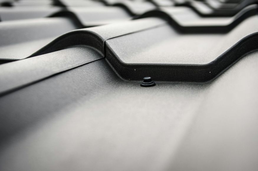 A close up of a black roof with a screw in it.