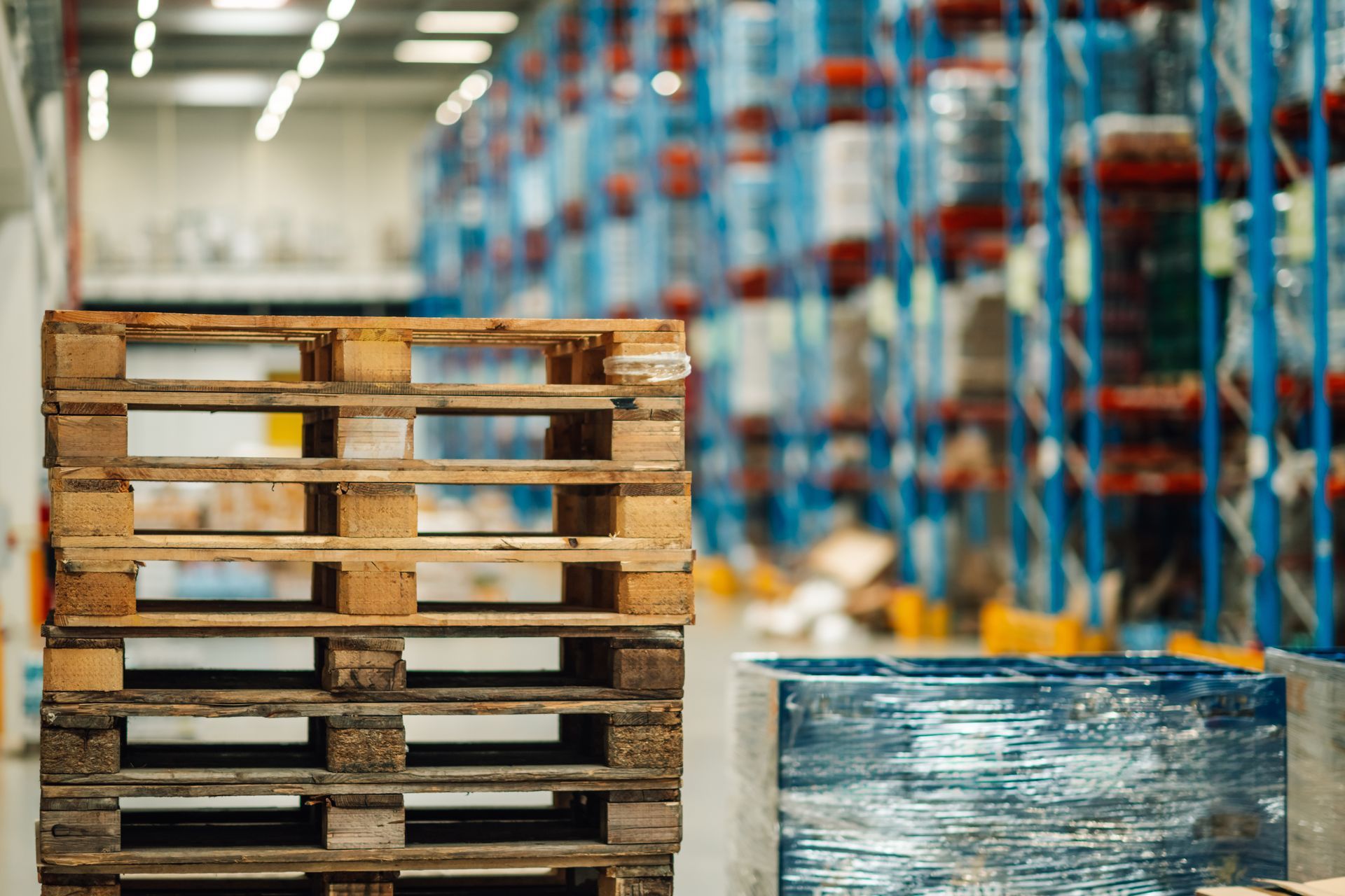 Cardboard boxes wrapped in plastic on a pallet, ready for shipping near a shipping container, forklift nearby.