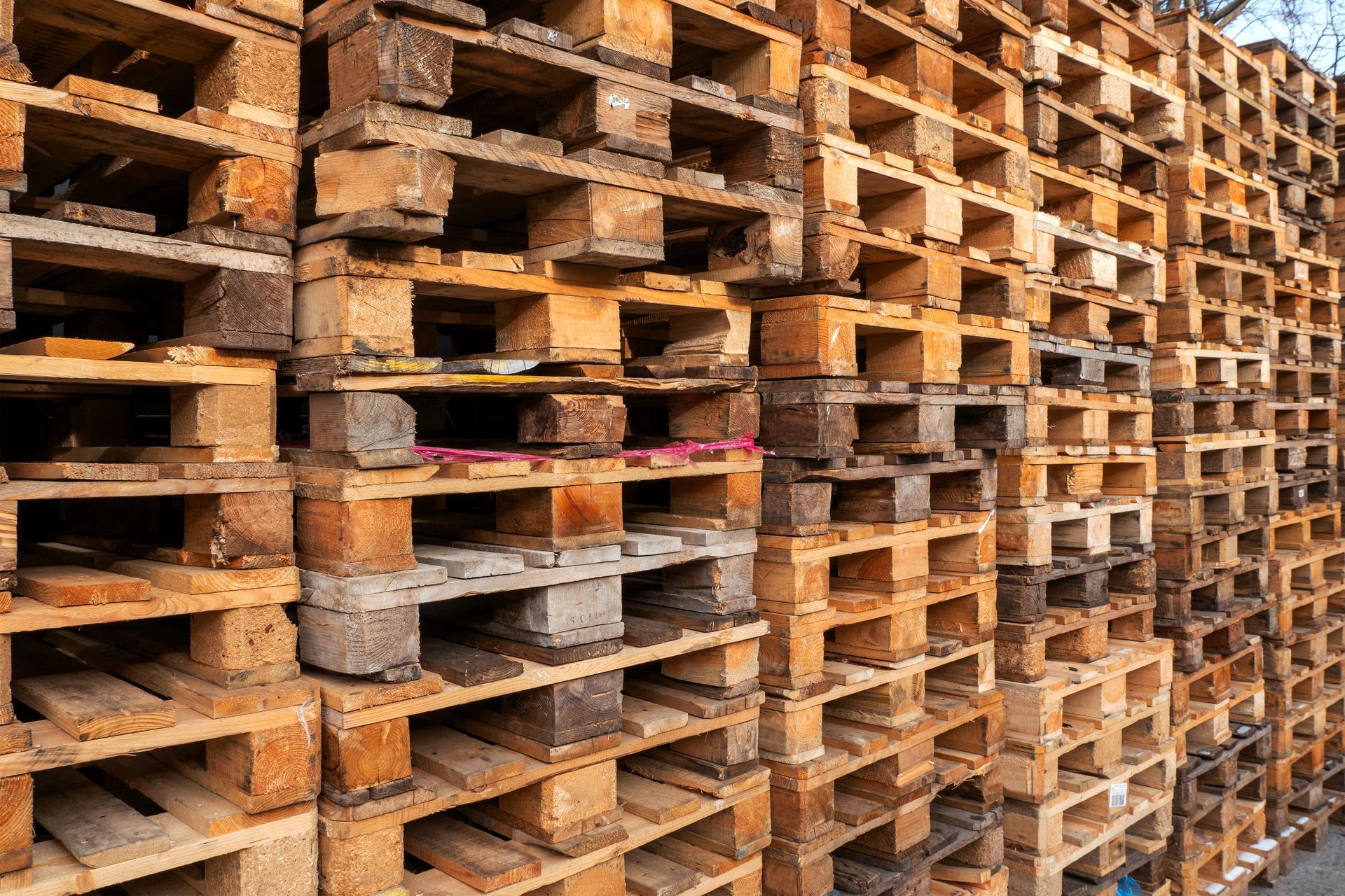 Stacked wooden shipping pallets filling the frame, creating a repeating pattern of light brown textured beams.