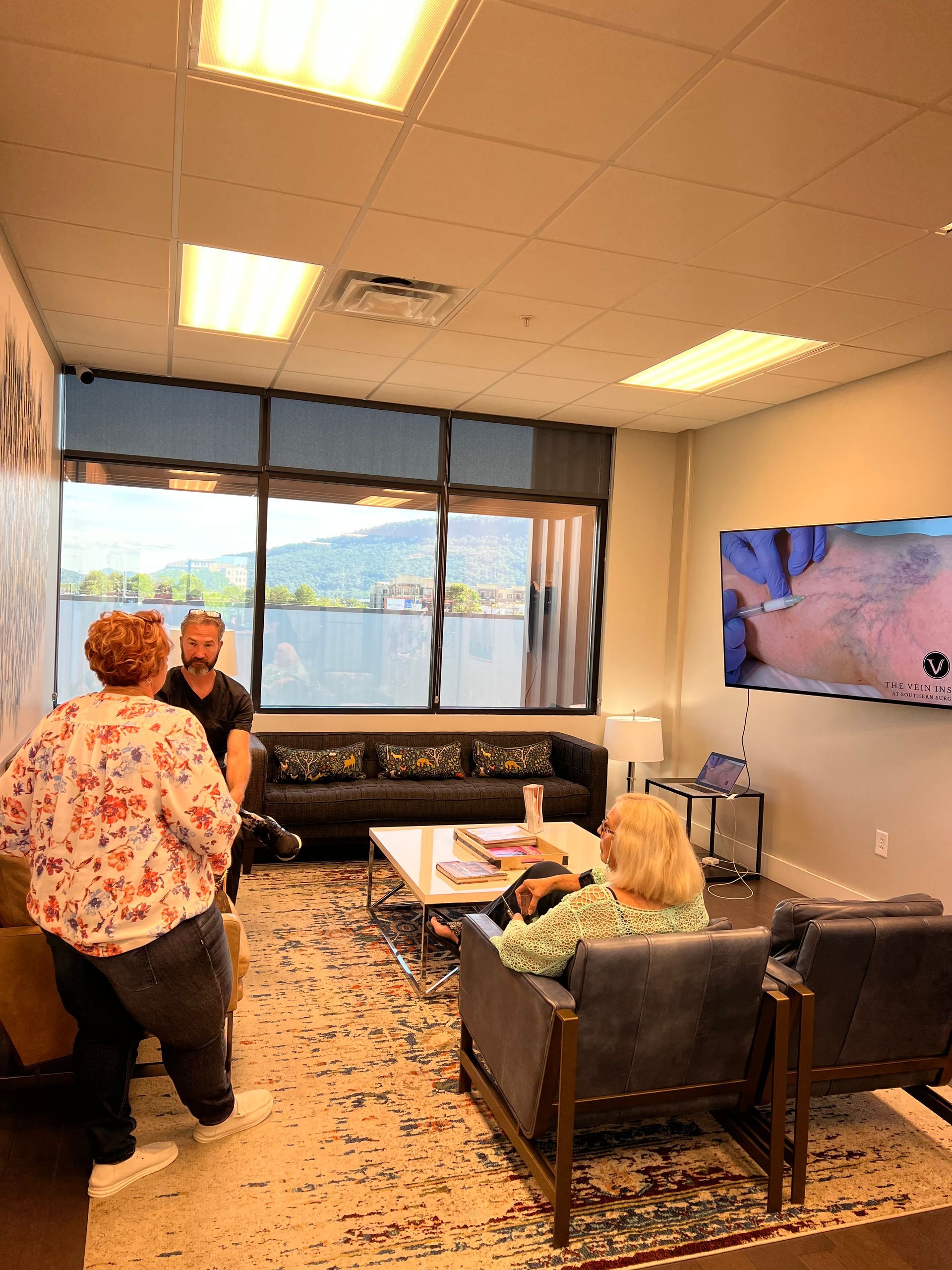 A group of people are sitting in a living room with a couch and chairs.