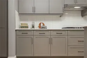 A kitchen with gray cabinets and white counter tops.