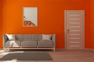 A living room with orange walls and a gray couch.