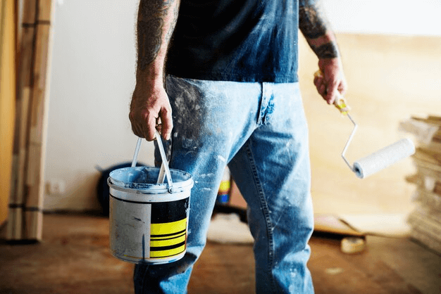 man holding a bucket of paint and a brush