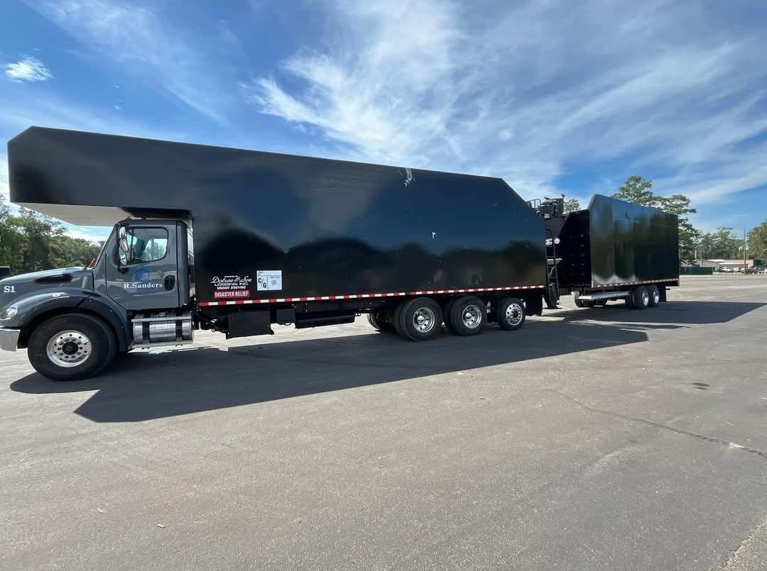A black truck with a trailer attached to it is parked on the side of the road.