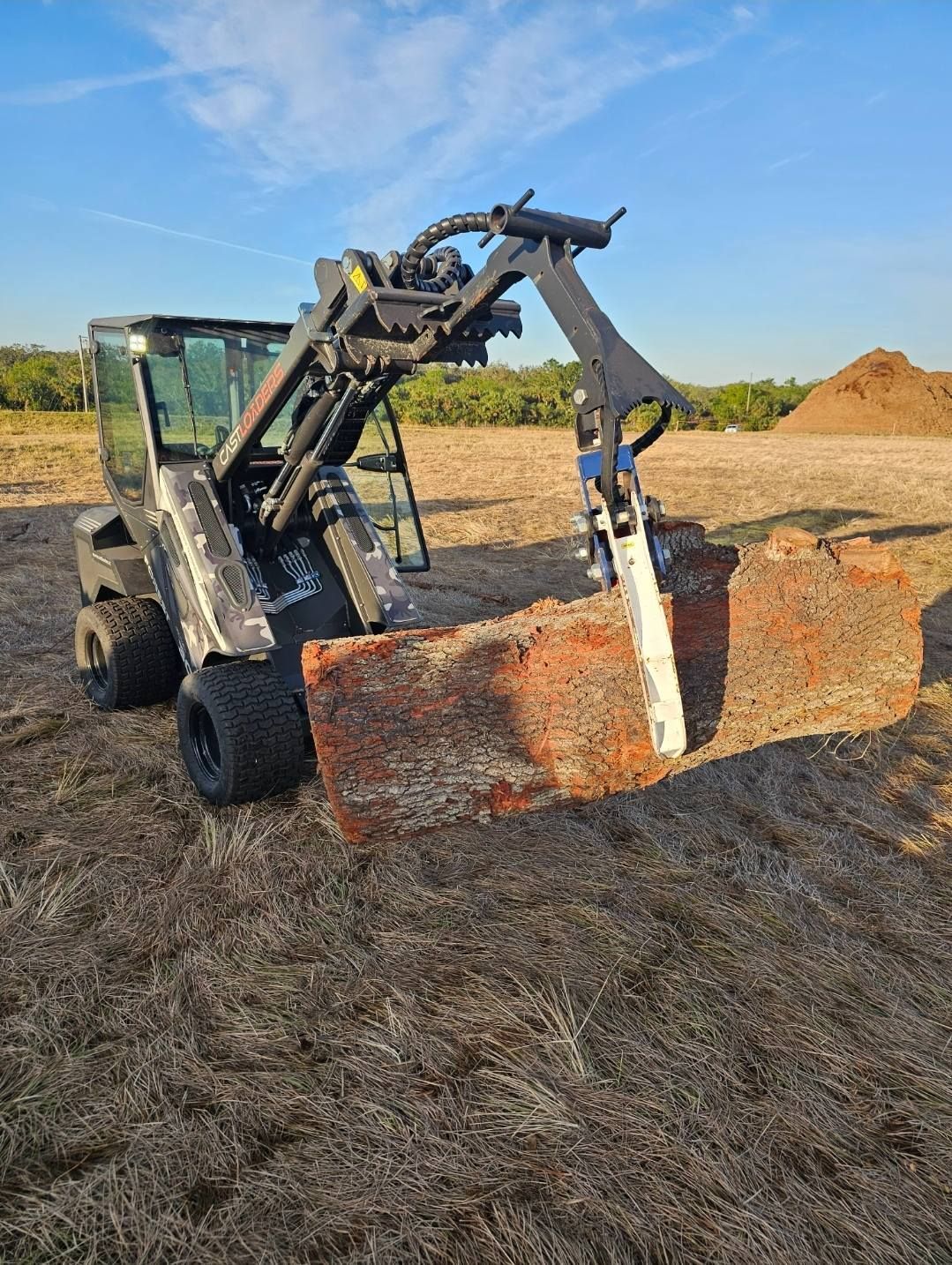 A bulldozer is cutting a large piece of wood in a field.