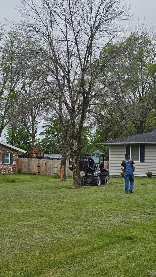 A man is mowing a lawn in front of a house.