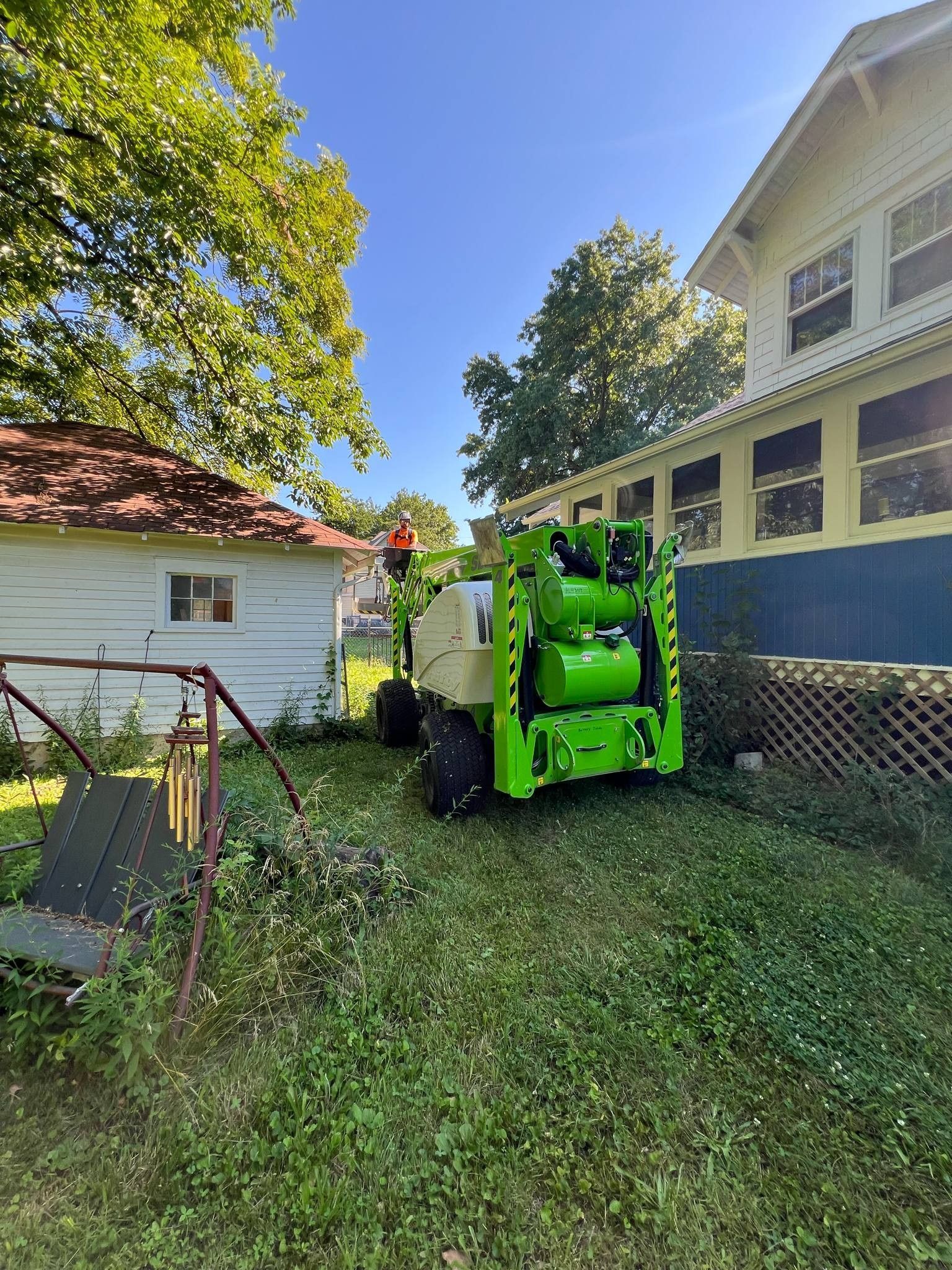 A green tractor is parked in front of a house.