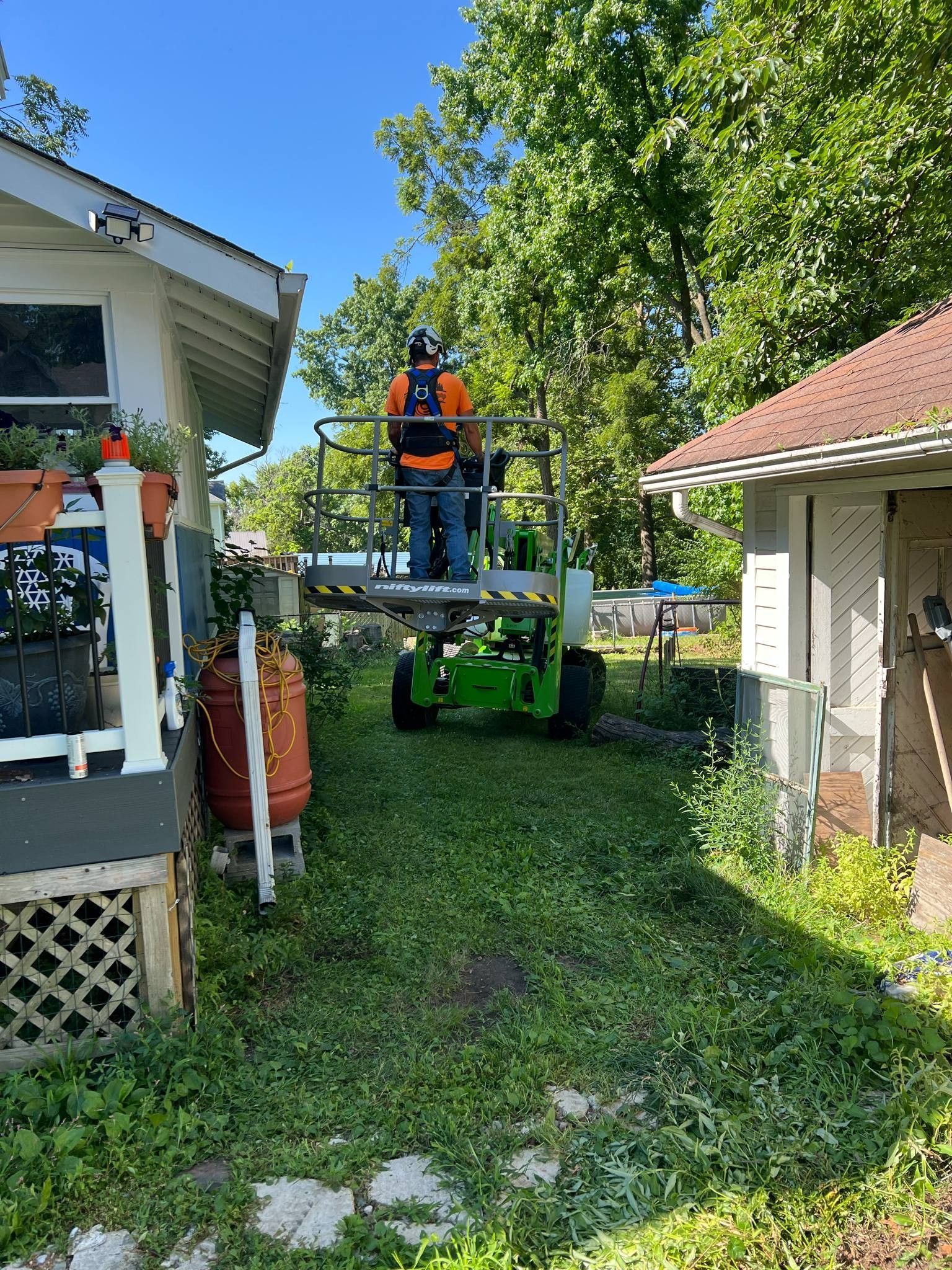 A man is standing on a lift in front of a house.