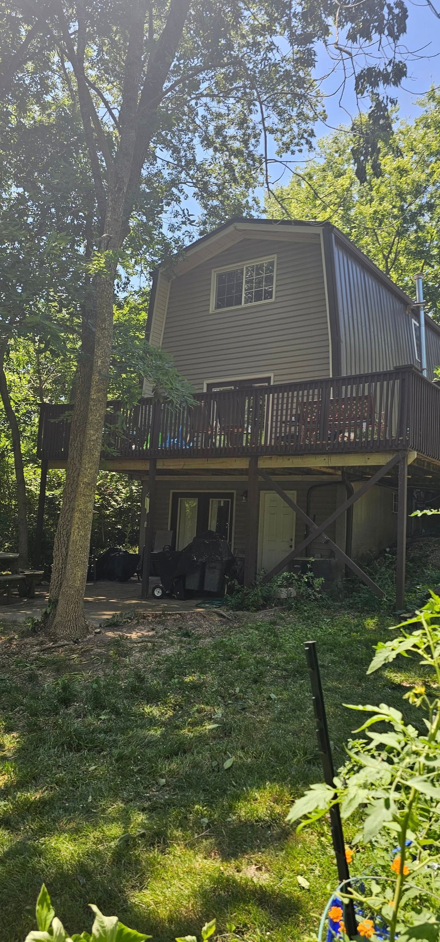 A house with a large deck is surrounded by trees.