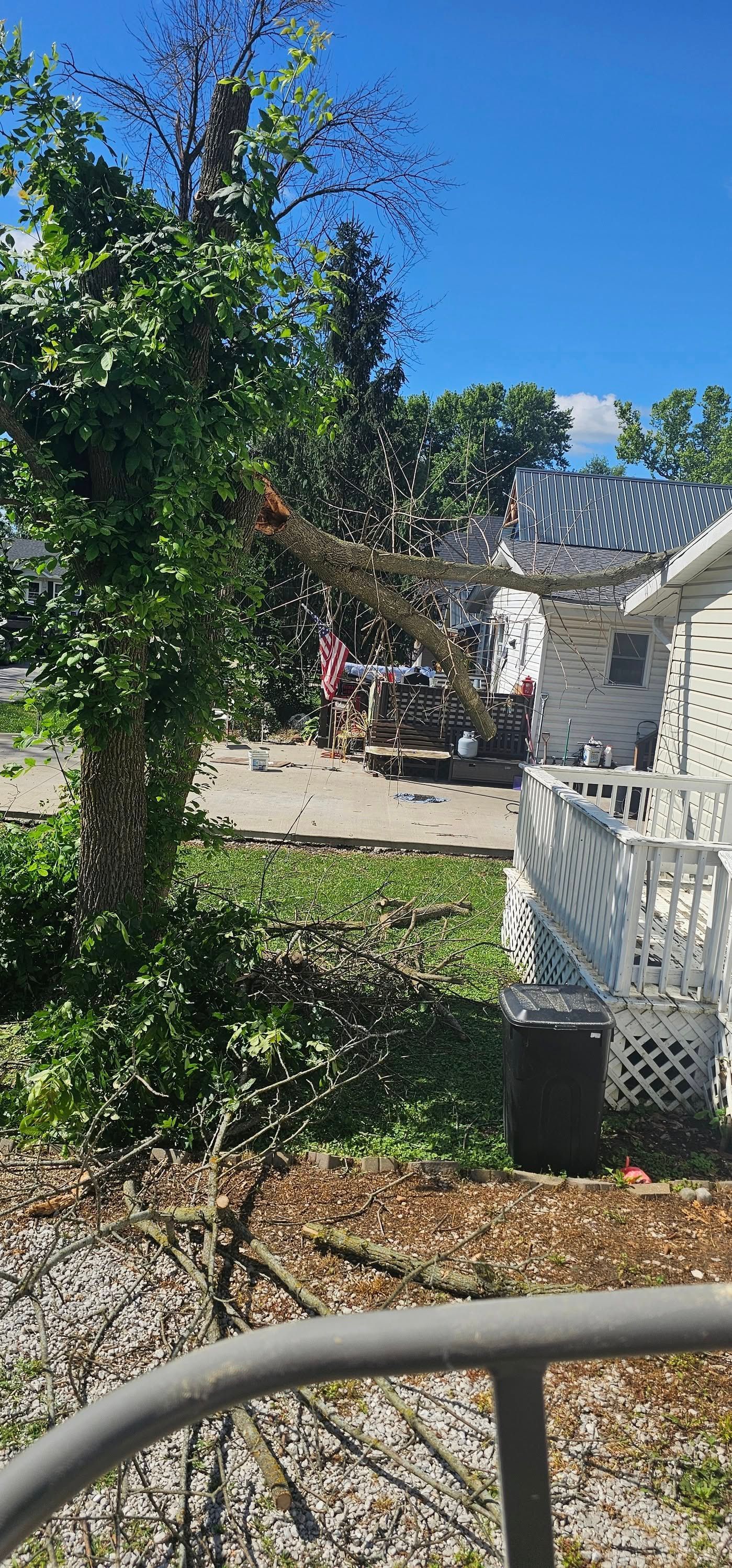 A white house with a broken tree in front of it.