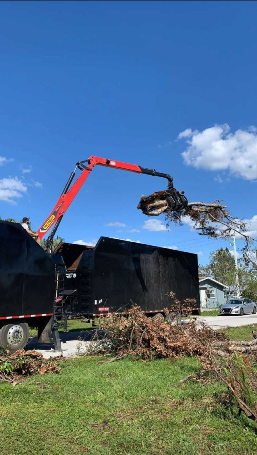 A crane is lifting a large piece of wood from a truck.