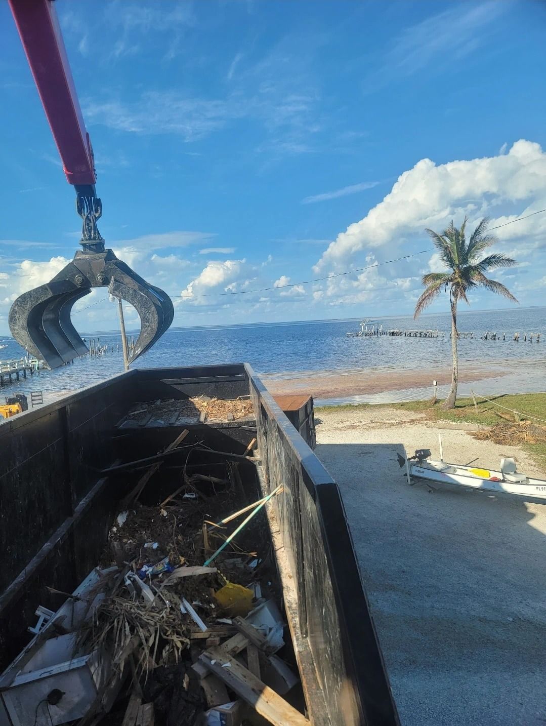 A crane is lifting a dumpster full of trash into the ocean.