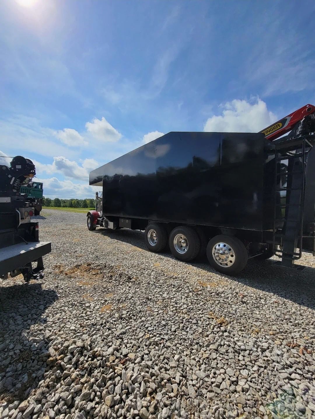 A black semi truck is parked in a gravel lot.