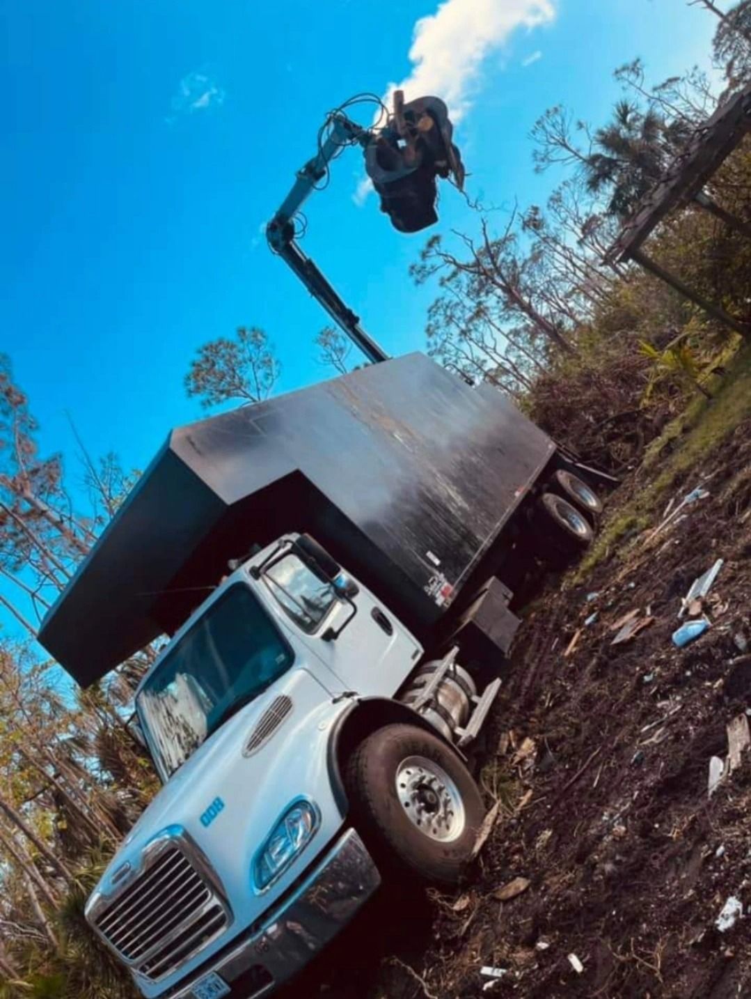A white truck is parked on the side of a dirt hill.