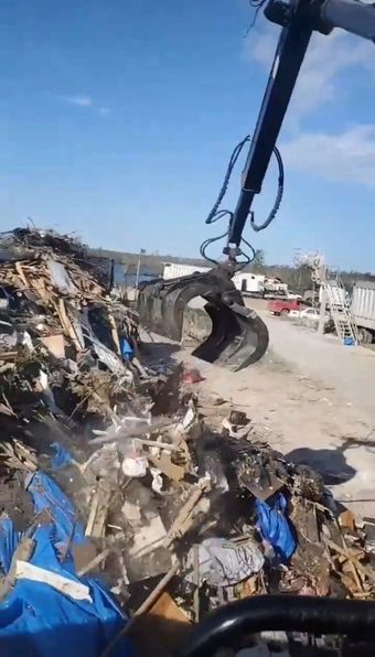 A large pile of trash is being picked up by a crane.