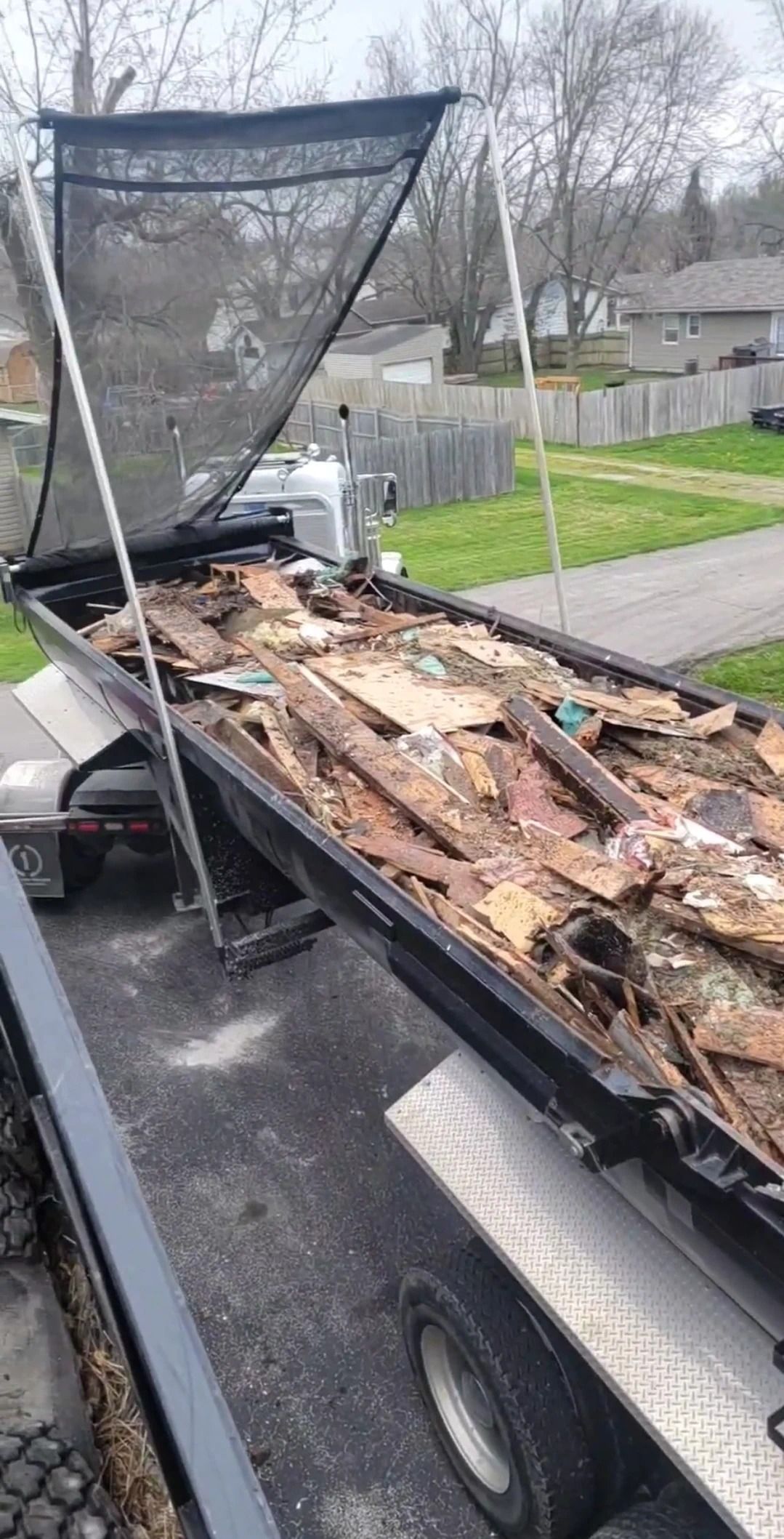 A trailer filled with wood is sitting on the side of the road.
