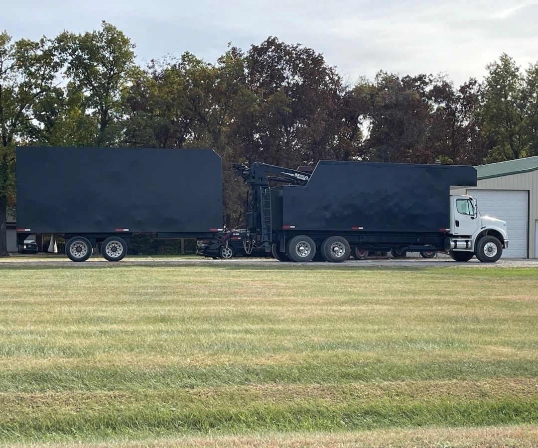 Two semi trucks are parked next to each other in a grassy field.