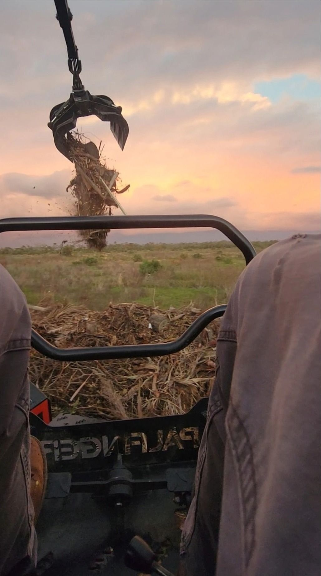 A person is riding a tractor in a field at sunset.