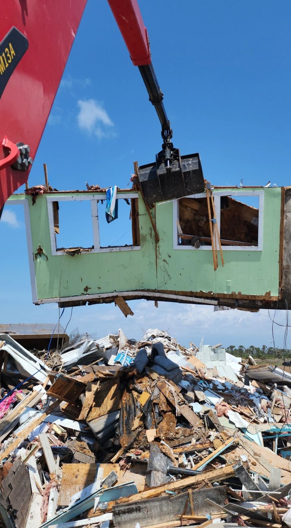 A large yellow excavator is demolishing a building.