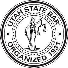 The seal of the utah state bar is black and white and shows a woman holding scales of justice.