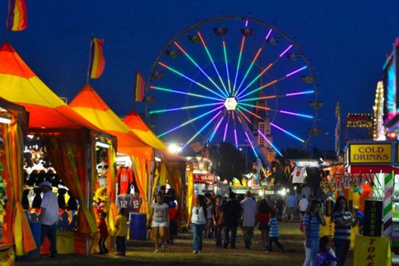 A carnival at night with a ferris wheel in the background