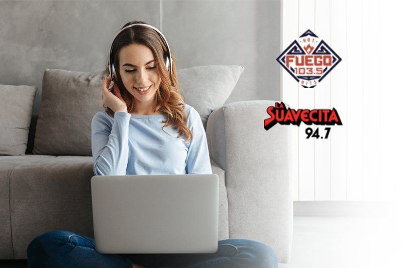 A woman wearing headphones is sitting on the floor using a laptop computer.