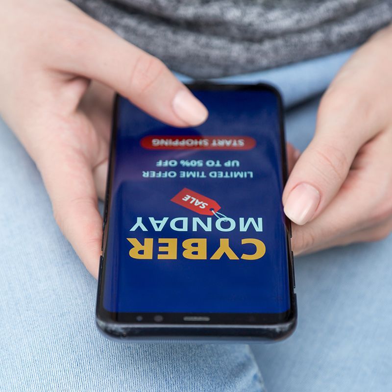 hands holding a mobile with cyber monday slogan on it