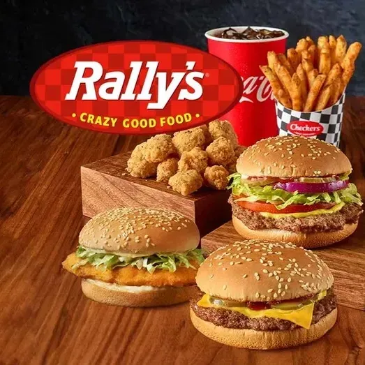 A bunch of hamburgers and french fries on a wooden table with a rally 's logo in the background