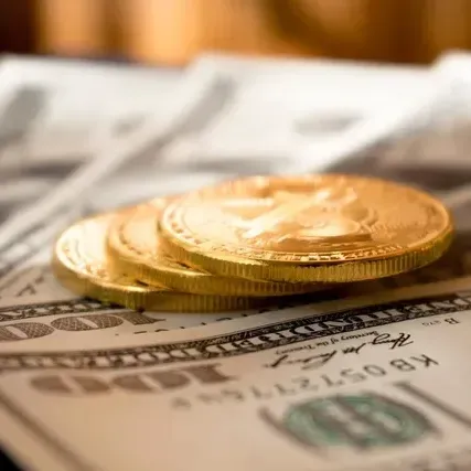 A stack of gold coins sitting on top of a pile of money.