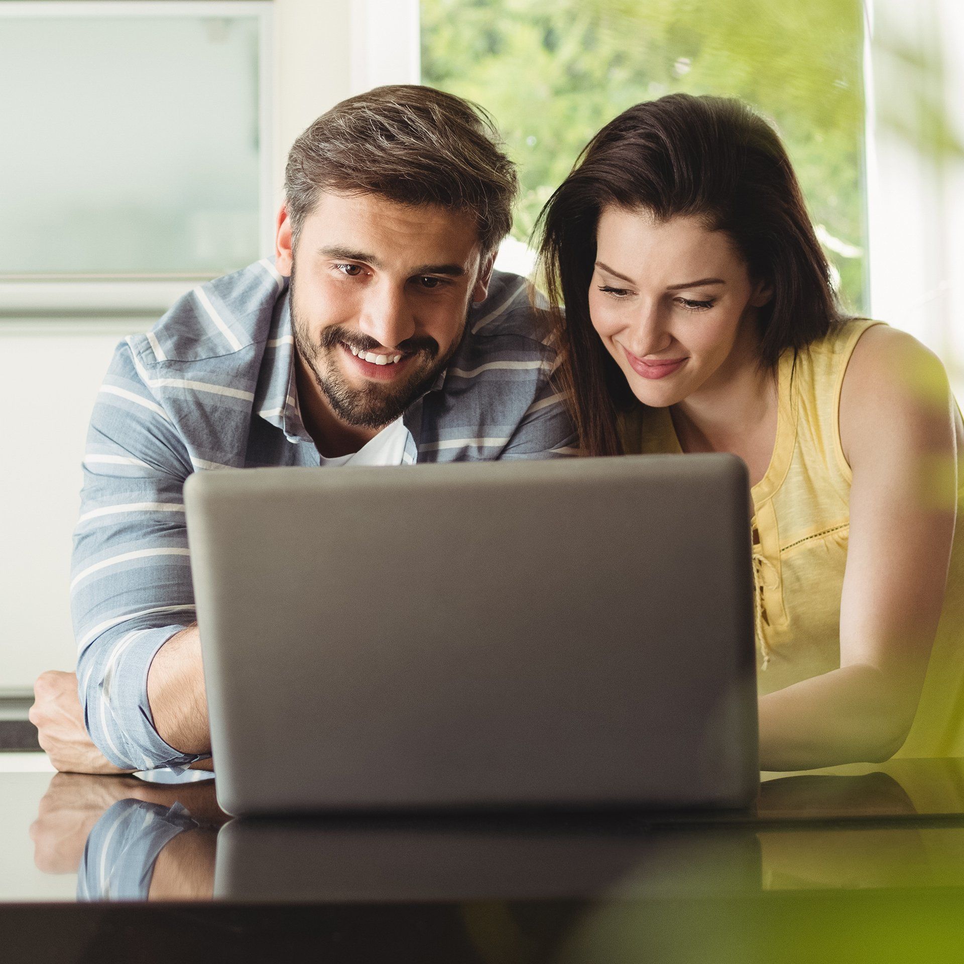 A man and a woman are looking at a laptop computer.