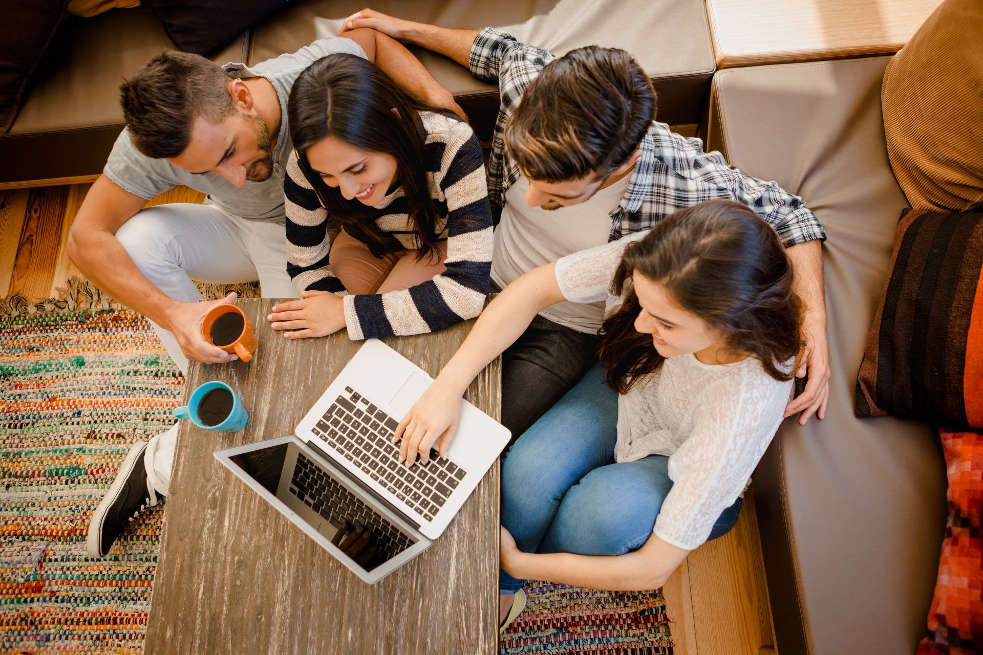 A group of Latino friends sits around a couch studying. Hispanic marketing is crucial to reach them!