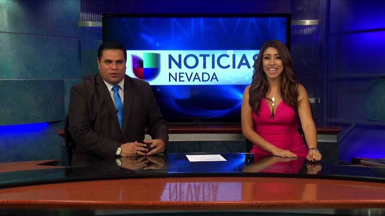 A man and a woman are sitting at a news desk in front of a screen that says noticia nevada