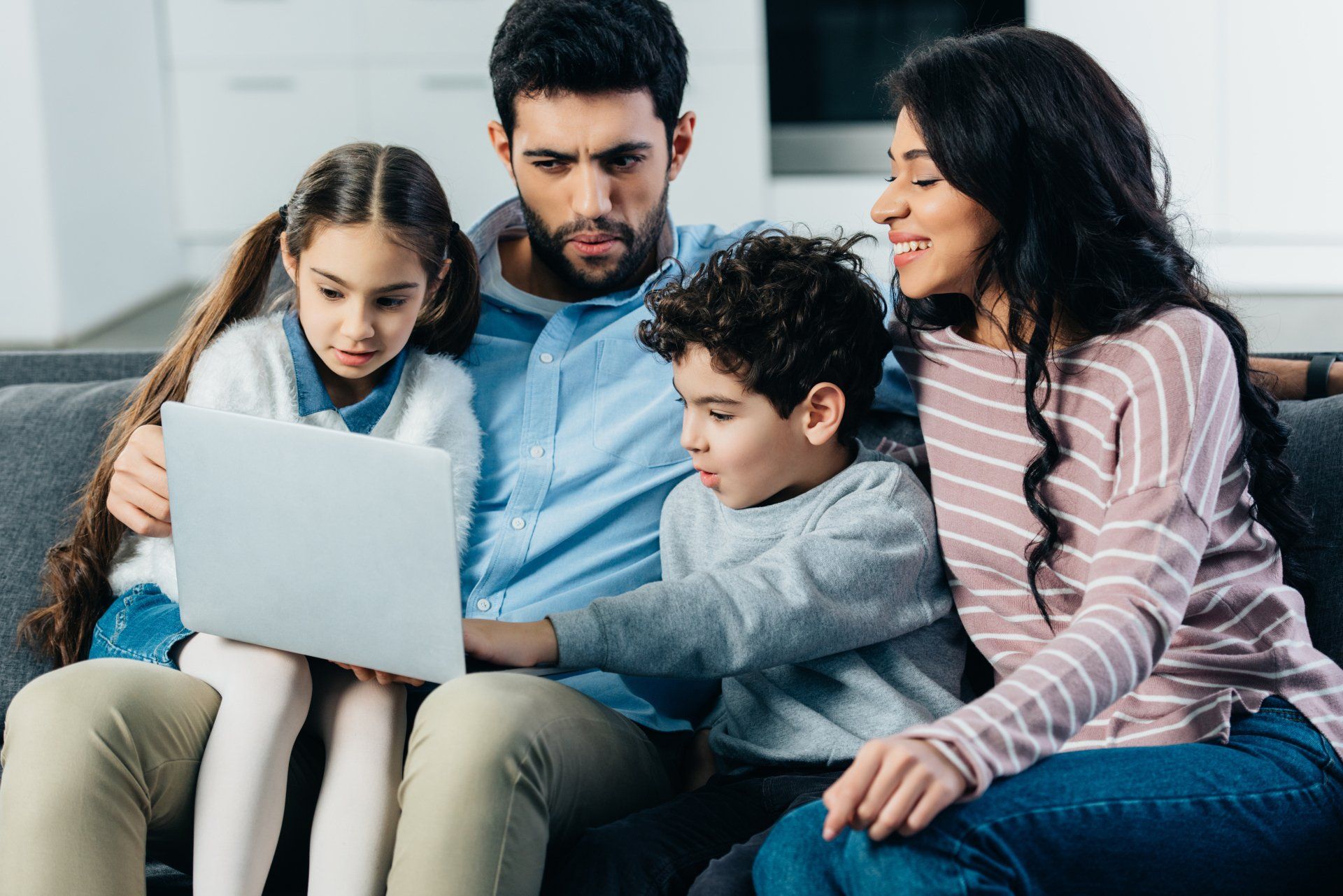 A Hispanic family looks at a laptop on their couch. Digital is a way to reach the Hispanic market.