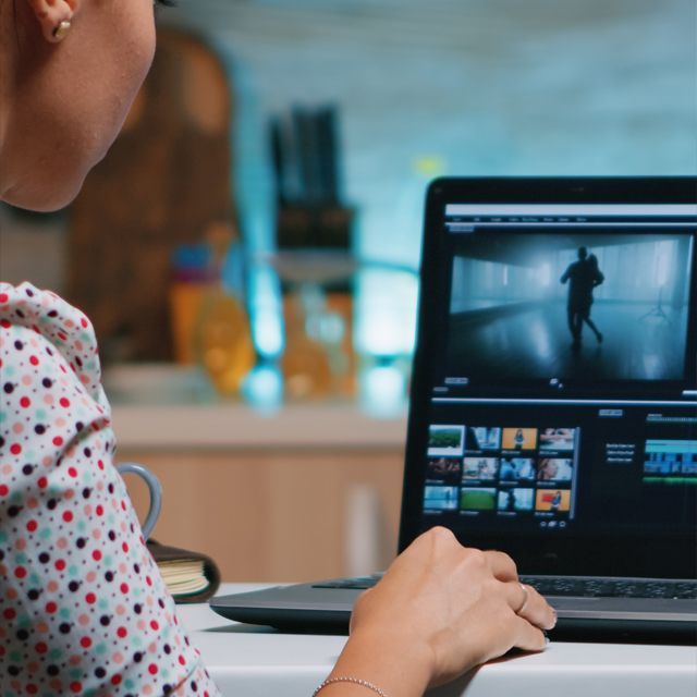 A woman is sitting at a table using a laptop computer.